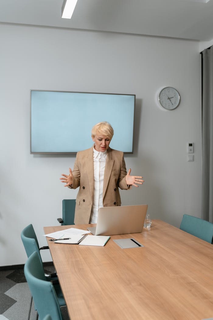 Businesswoman in beige blazer presenting in a modern office setting.